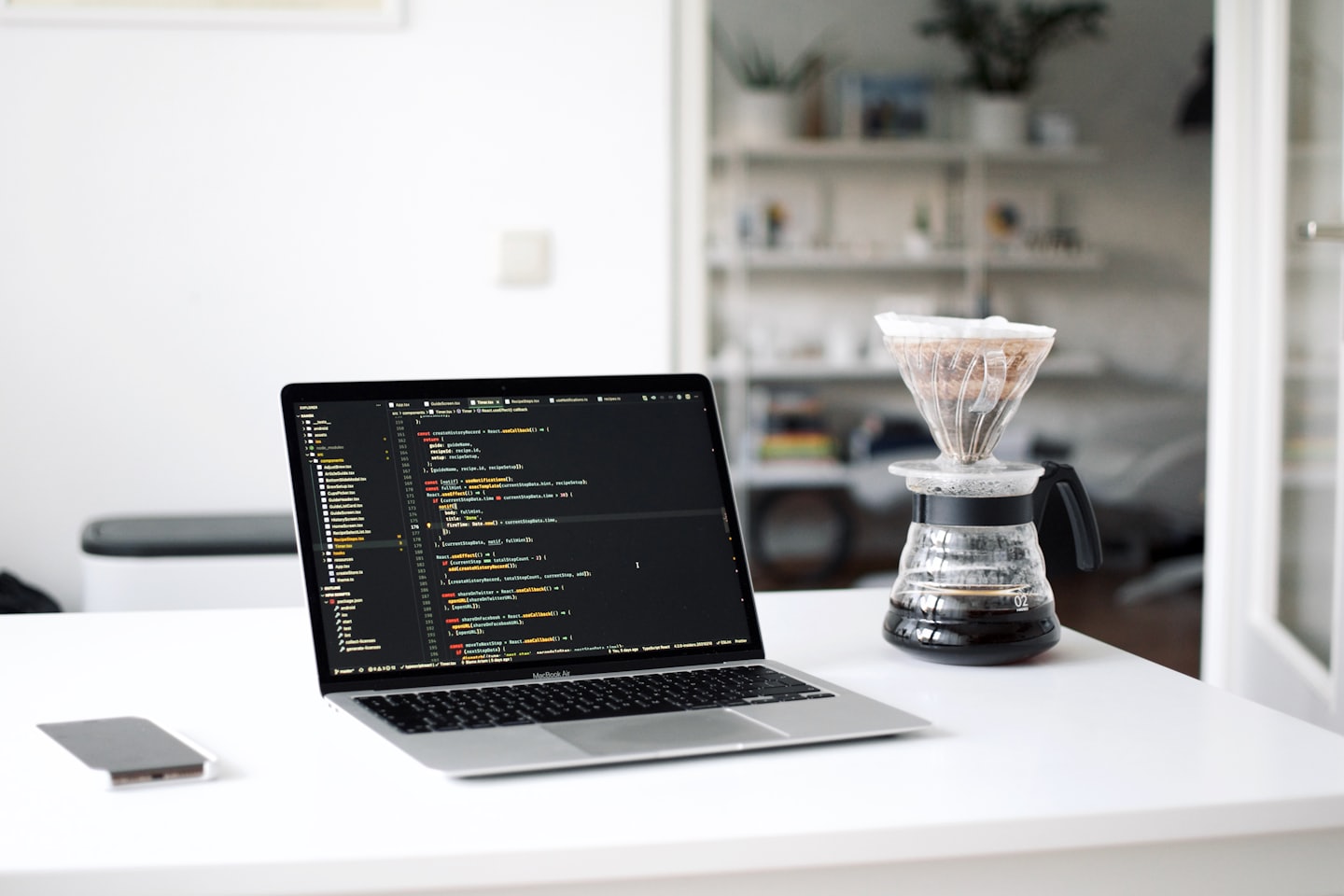 Ein Laptop mit Code auf einem Schreibtisch mit Kaffee.