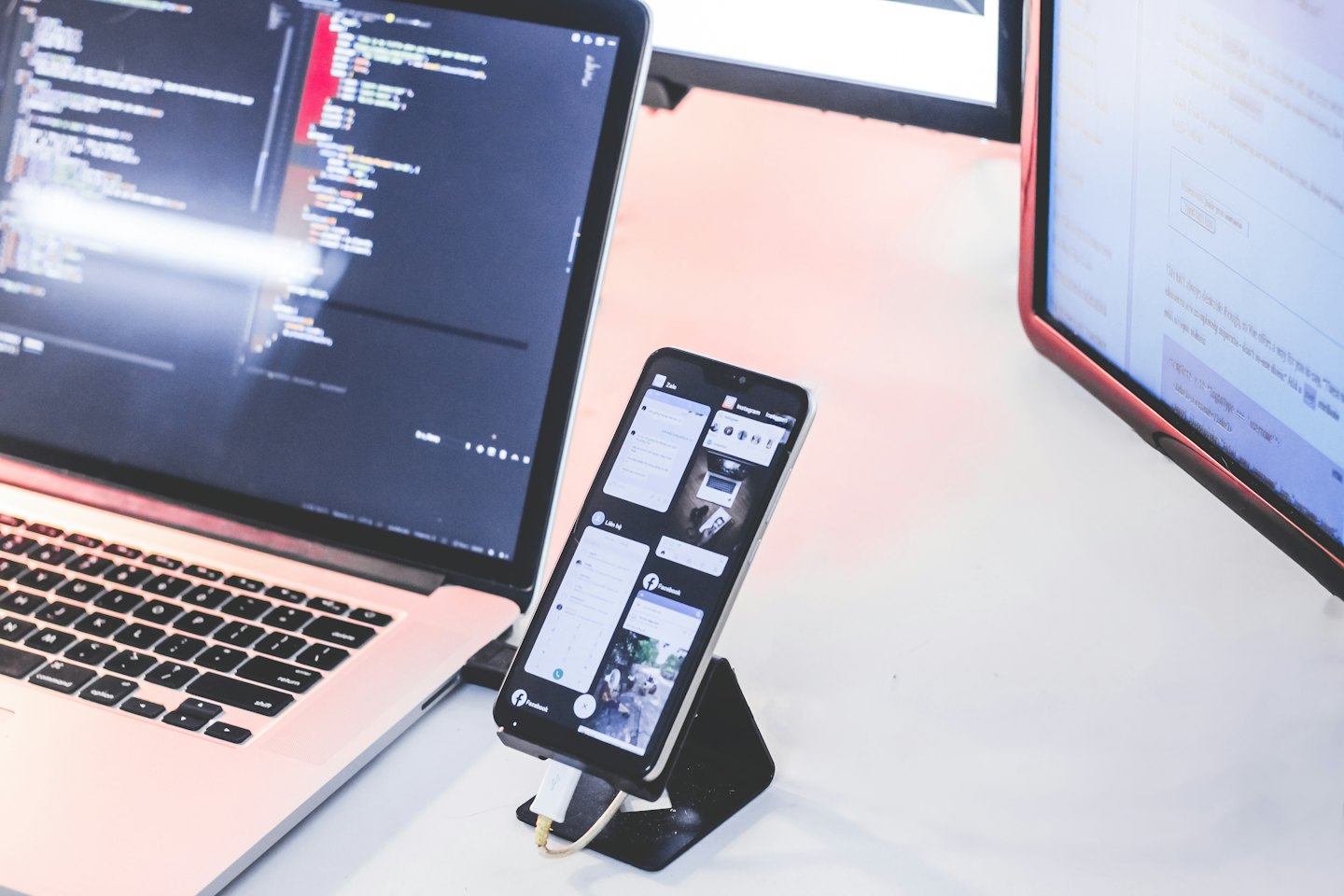 Laptop und Monitor mit Code auf einem weißen Schreibtisch.