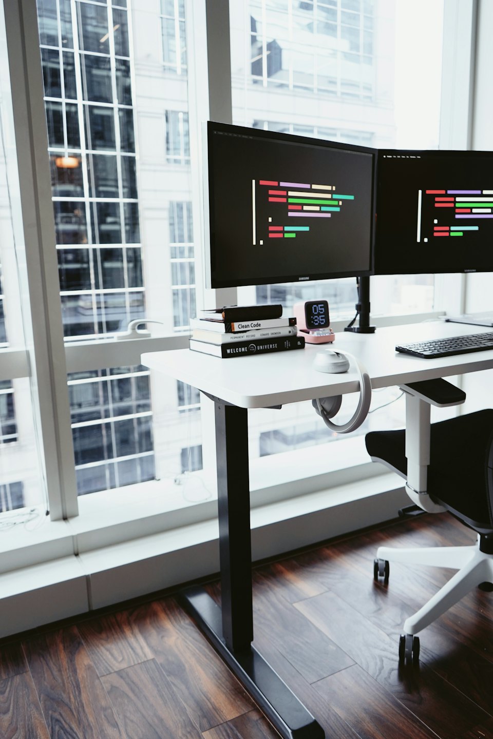 Stehschreibtisch mit Computern und Büchern am Stadtrandfenster.